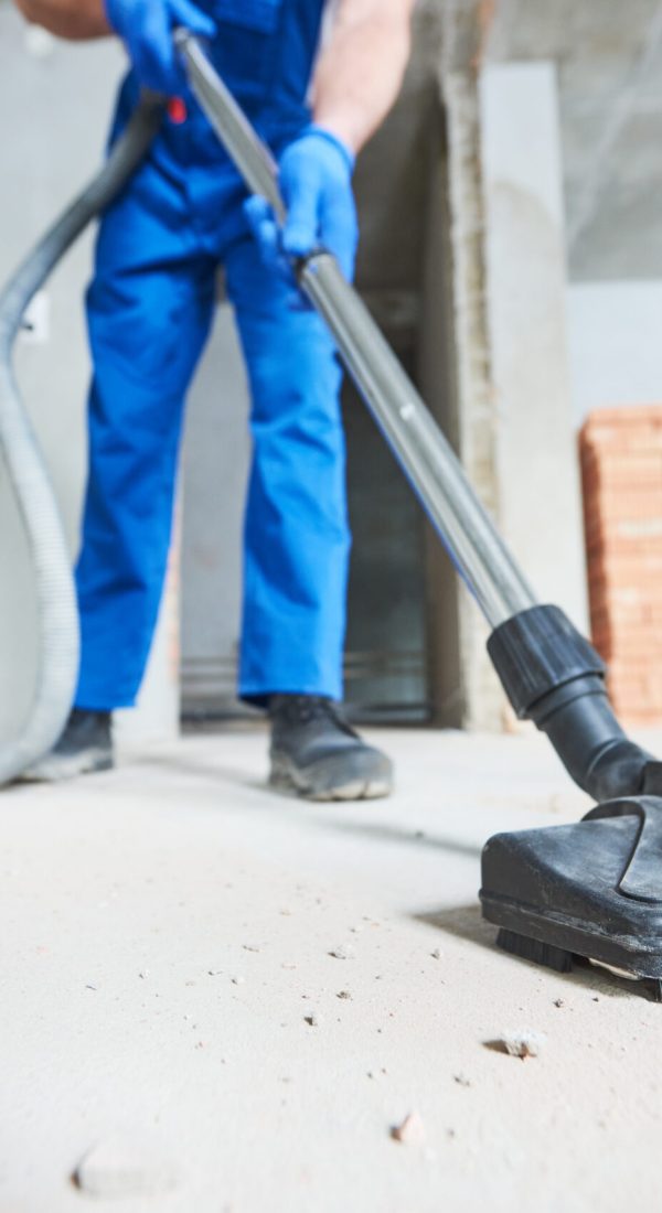 young woman cleaning and removing construction dust with vacuum cleaner after repair