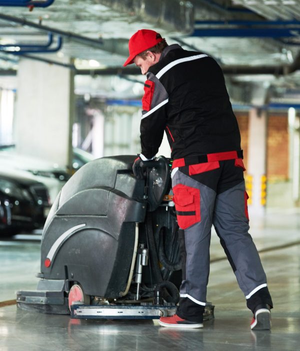 cleaning service. worker with machine cleaning floor in parking garage