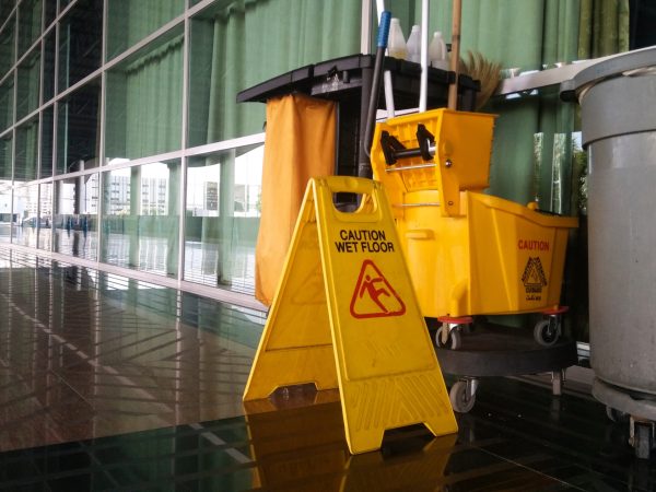 The warning signs cleaning and caution wet floor in the building and janitorial car parked in back to remind people to walk safely.